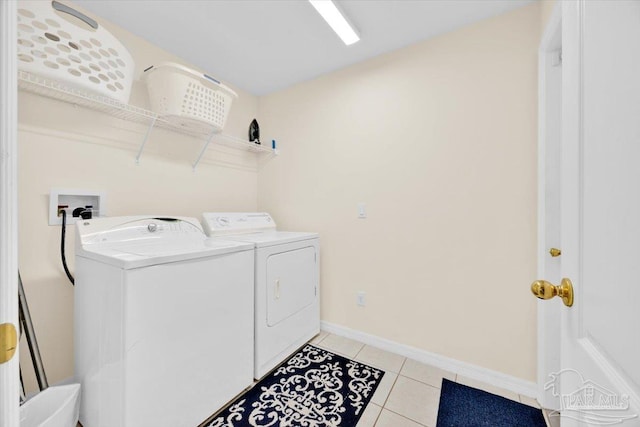 clothes washing area with washer and dryer and light tile patterned floors