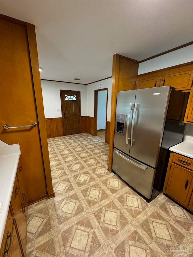 kitchen featuring wood walls, ornamental molding, and stainless steel refrigerator with ice dispenser