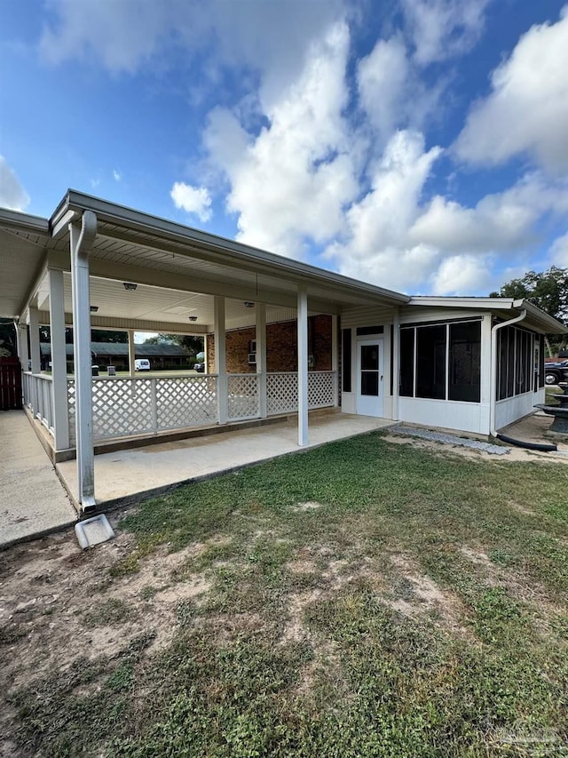 back of house featuring a yard and a sunroom