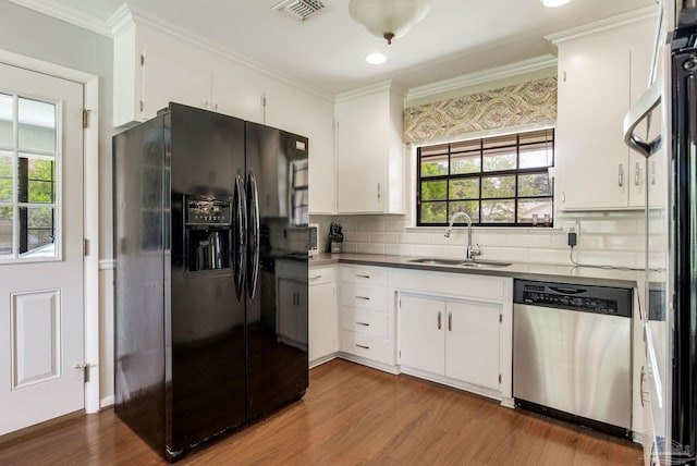6031 Keating Rd, Pensacola, FL 32504 - kitchen featuring black fridge, stainless steel dishwasher, wood finished floors, tasteful backsplash, and crown molding