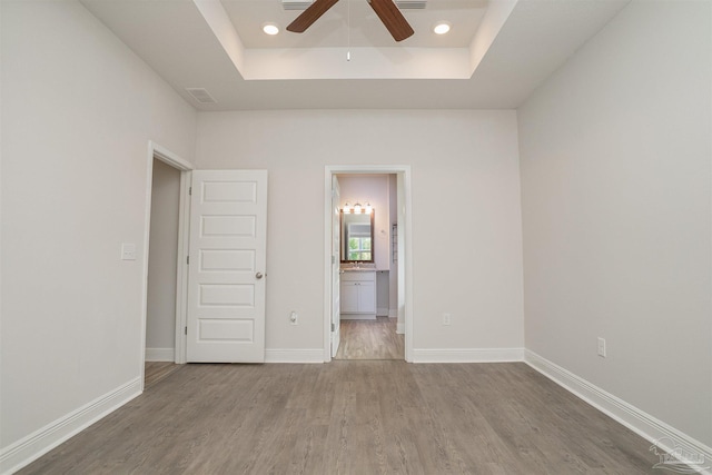 spare room featuring a ceiling fan, recessed lighting, wood finished floors, a tray ceiling, and visible vents