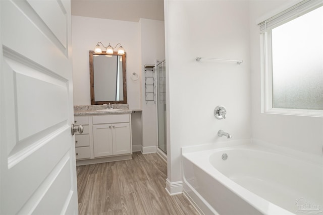 bathroom with vanity, baseboards, a shower stall, wood finished floors, and a bath