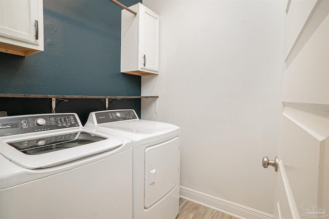 clothes washing area featuring washer and dryer, baseboards, light wood-type flooring, and cabinet space