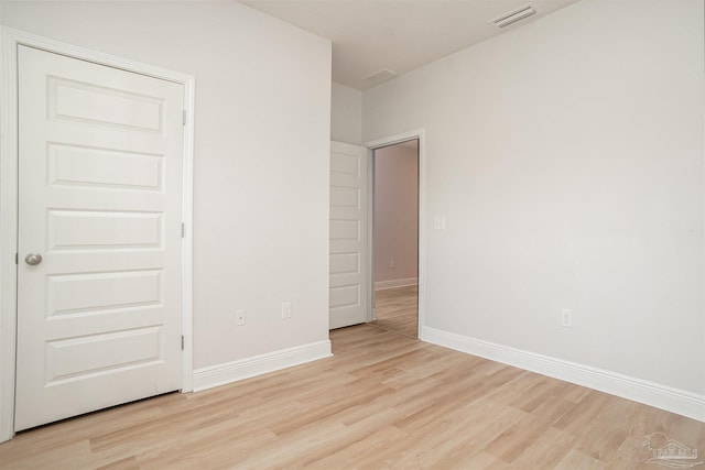 spare room with baseboards, light wood finished floors, and visible vents