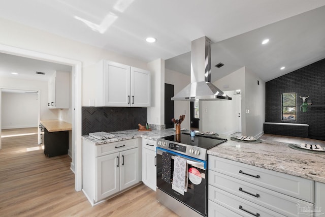 kitchen featuring vaulted ceiling, stainless steel range with electric stovetop, island exhaust hood, and white cabinets