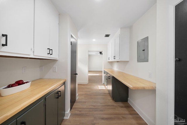 kitchen featuring built in desk, white cabinetry, electric panel, ceiling fan, and light hardwood / wood-style flooring