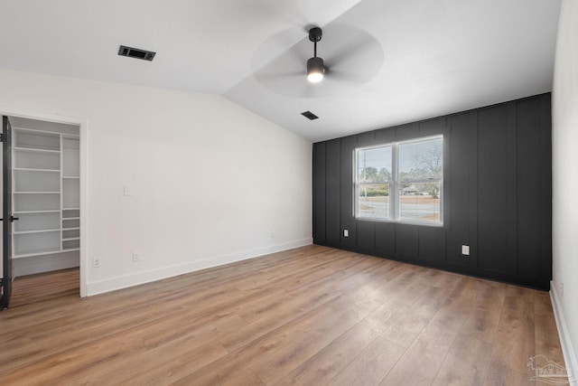 empty room with vaulted ceiling, ceiling fan, and light wood-type flooring