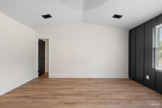 empty room featuring lofted ceiling and light hardwood / wood-style floors