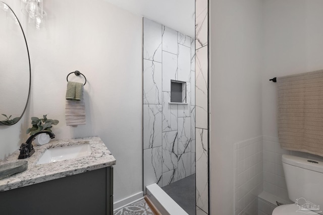 bathroom with vanity, toilet, and a tile shower