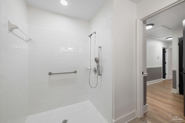 bathroom with tiled shower and hardwood / wood-style floors