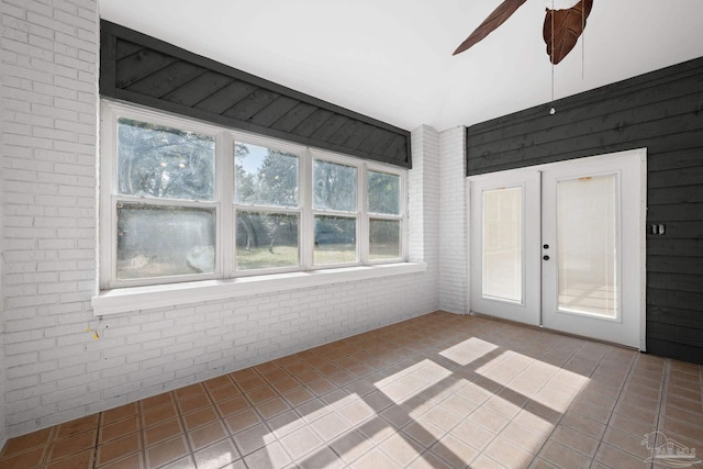 empty room featuring tile patterned floors, french doors, ceiling fan, and brick wall