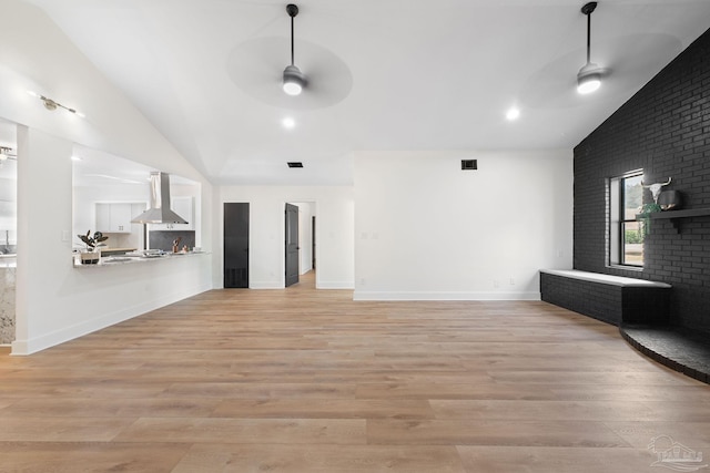 unfurnished living room featuring a fireplace, vaulted ceiling, ceiling fan, and light wood-type flooring