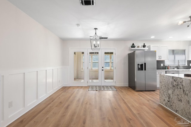 unfurnished dining area with french doors, a healthy amount of sunlight, sink, and light hardwood / wood-style flooring