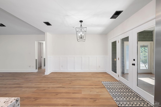 dining space with a notable chandelier, light hardwood / wood-style floors, and french doors