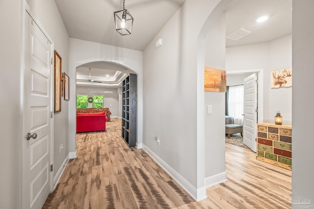 8056 Stream Ridge Rd, Pensacola, FL 32526 - hall featuring arched walkways, wood finished floors, baseboards, and a tray ceiling
