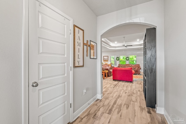 8056 Stream Ridge Rd, Pensacola, FL 32526 - hallway with arched walkways, baseboards, a raised ceiling, and light wood-type flooring