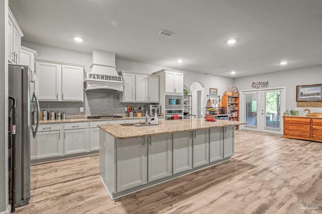 8056 Stream Ridge Rd, Pensacola, FL 32526 - kitchen with appliances with stainless steel finishes, custom range hood, light wood-type flooring, a textured ceiling, and an island with sink