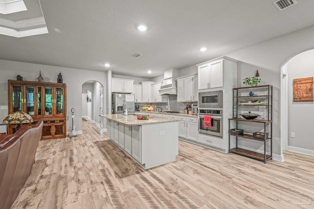 8056 Stream Ridge Rd, Pensacola, FL 32526 - kitchen featuring stainless steel appliances, arched walkways, custom exhaust hood, baseboards, and light wood-style floors