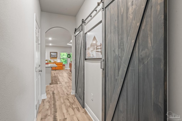 8056 Stream Ridge Rd, Pensacola, FL 32526 - hallway with a barn door, light wood-style floors, baseboards, arched walkways, and recessed lighting