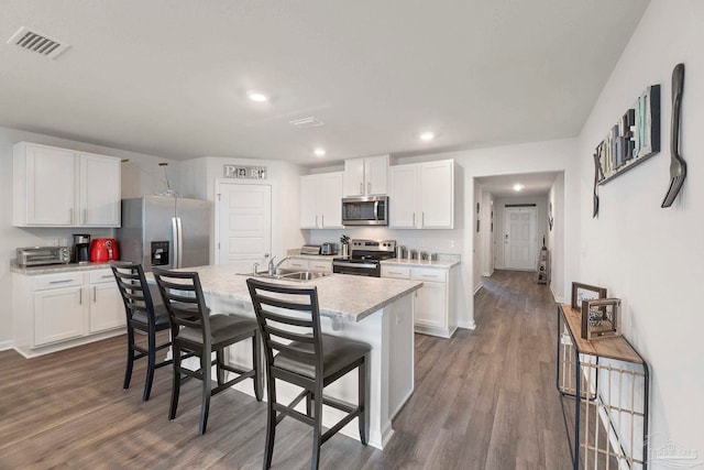 6173 Native Dancer Way, Pensacola, FL 32526 - kitchen featuring appliances with stainless steel finishes, a kitchen breakfast bar, light countertops, dark wood finished floors, and white cabinetry