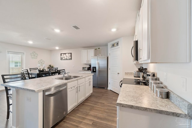 6173 Native Dancer Way, Pensacola, FL 32526 - kitchen featuring appliances with stainless steel finishes, dark wood-style flooring, white cabinets, an island with sink, and a kitchen bar