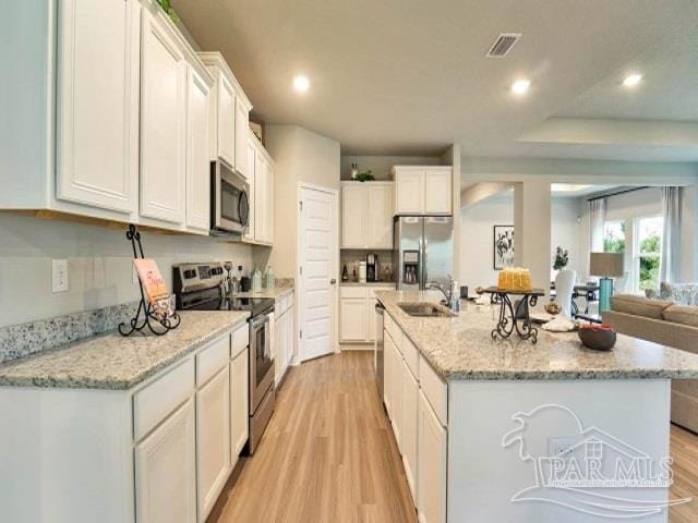 kitchen featuring white cabinetry, sink, an island with sink, light hardwood / wood-style floors, and appliances with stainless steel finishes