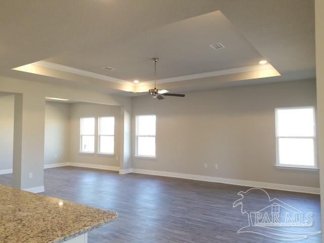 spare room featuring a raised ceiling, ceiling fan, crown molding, and dark wood-type flooring