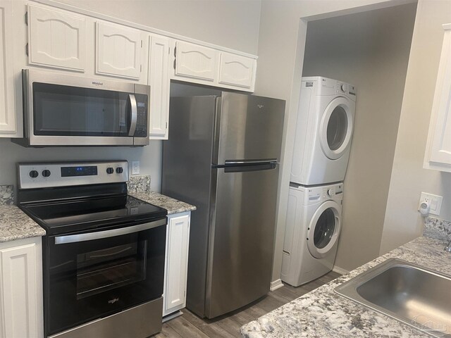 kitchen with white cabinetry, stacked washer and dryer, and stainless steel appliances