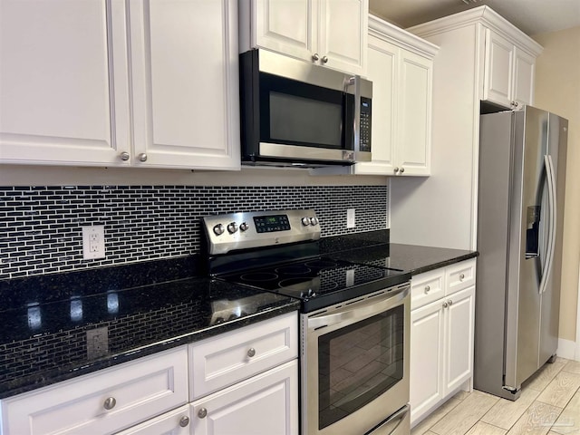 1792 Galvez Dr, Gulf Breeze, FL 32563 - kitchen with white cabinetry, dark stone countertops, appliances with stainless steel finishes, light hardwood / wood-style floors, and backsplash