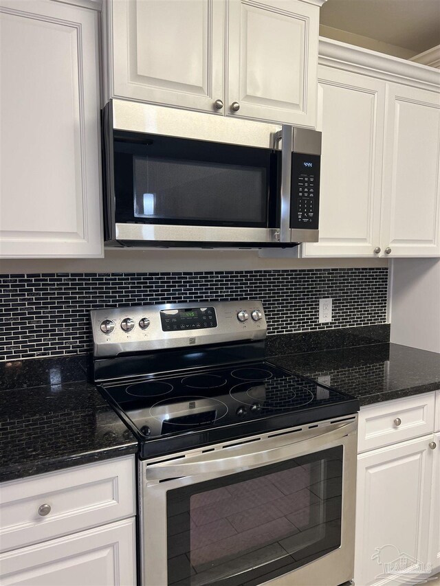 1792 Galvez Dr, Gulf Breeze, FL 32563 - kitchen with dark stone countertops, stainless steel appliances, decorative backsplash, and white cabinets