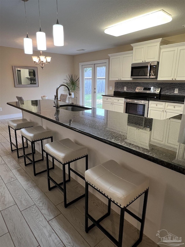 1792 Galvez Dr, Gulf Breeze, FL 32563 - kitchen with appliances with stainless steel finishes, white cabinetry, sink, a kitchen bar, and decorative backsplash