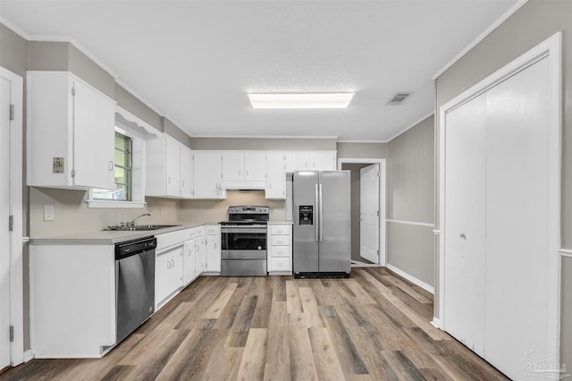 2382 Ryale Rd, Cantonment, FL 32533 - kitchen with appliances with stainless steel finishes, light wood-style flooring, light countertops, white cabinets, and crown molding