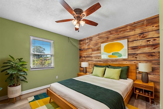 2382 Ryale Rd, Cantonment, FL 32533 - bedroom featuring wood walls, baseboards, wood finished floors, an accent wall, and a textured ceiling