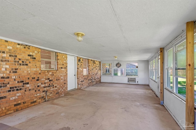 2382 Ryale Rd, Cantonment, FL 32533 - unfurnished sunroom featuring brick wall, a textured ceiling, unfinished concrete floors, and a wall mounted air conditioner