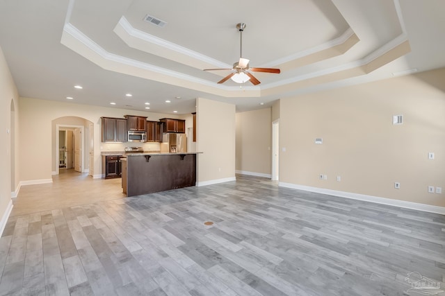 unfurnished living room featuring light wood-type flooring, a raised ceiling, and crown molding