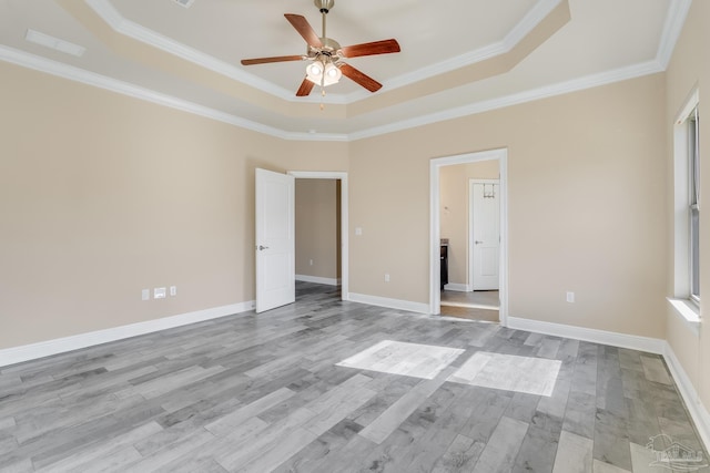 unfurnished bedroom with a tray ceiling, crown molding, light hardwood / wood-style flooring, and ceiling fan