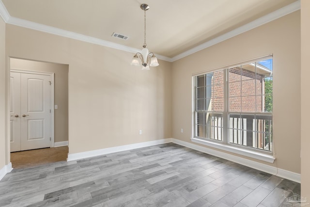 empty room with light wood-type flooring, ornamental molding, and a chandelier