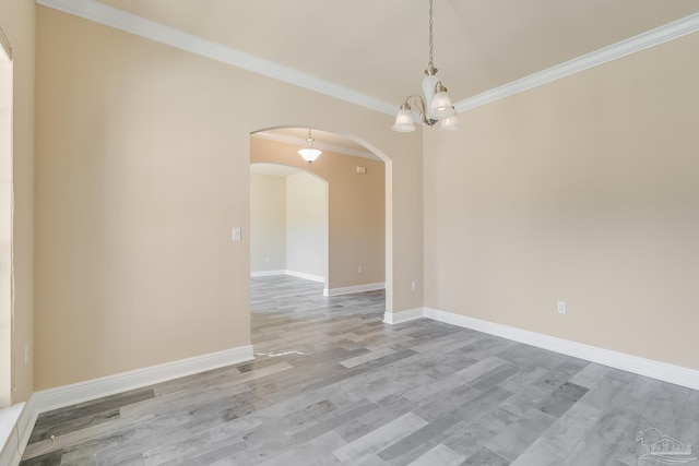 spare room featuring wood-type flooring, a notable chandelier, and ornamental molding