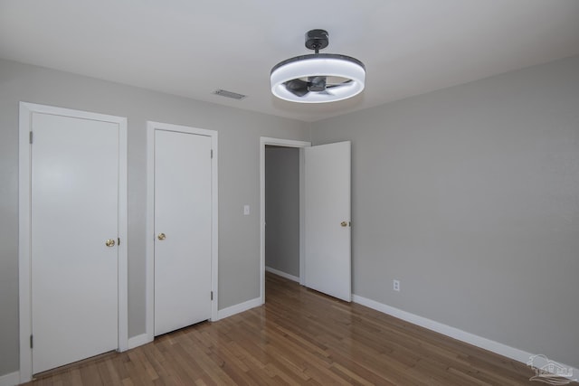 unfurnished bedroom with visible vents, baseboards, and wood finished floors