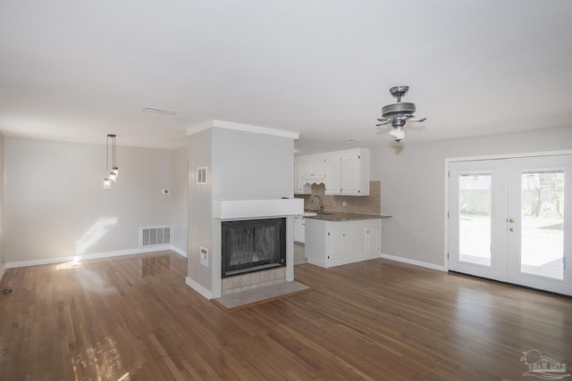 unfurnished living room with wood finished floors, visible vents, and baseboards