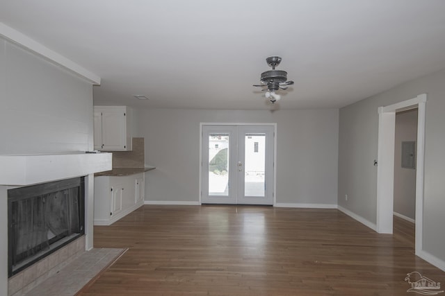 unfurnished living room with wood finished floors, electric panel, french doors, and baseboards