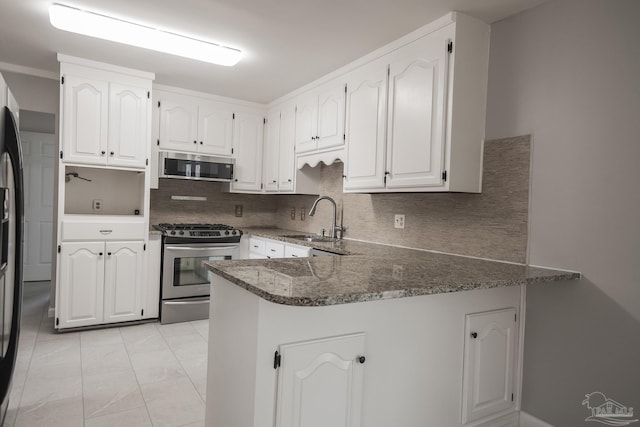 kitchen featuring dark stone countertops, a peninsula, a sink, appliances with stainless steel finishes, and marble finish floor