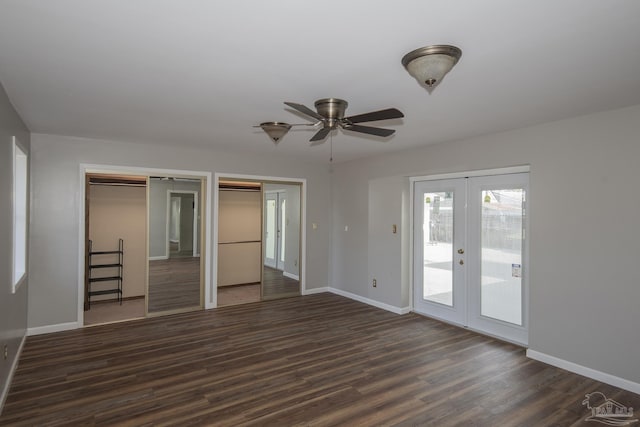 interior space featuring dark wood-style floors, baseboards, access to exterior, french doors, and multiple closets