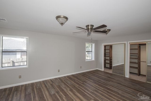 unfurnished bedroom with visible vents, baseboards, multiple closets, and wood finished floors