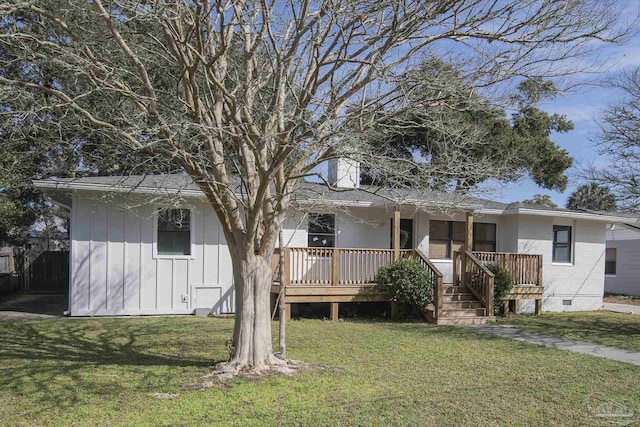 back of property with crawl space, a lawn, board and batten siding, and brick siding