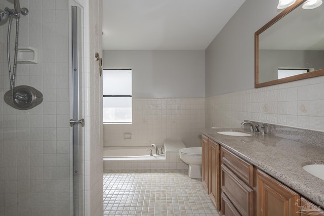 full bathroom featuring tile walls, double vanity, a tile shower, and a sink