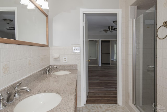 full bath featuring a shower stall, tile walls, a ceiling fan, and a sink