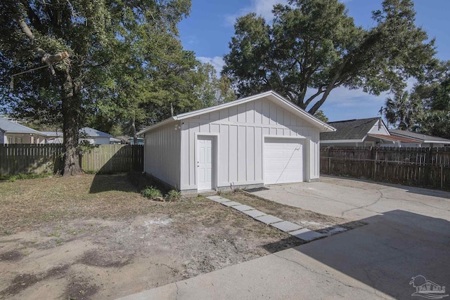 detached garage with concrete driveway and fence