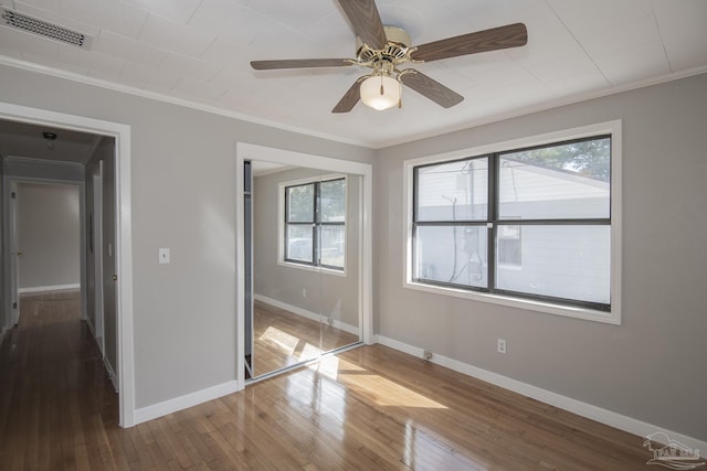 unfurnished bedroom with visible vents, baseboards, hardwood / wood-style flooring, a closet, and crown molding