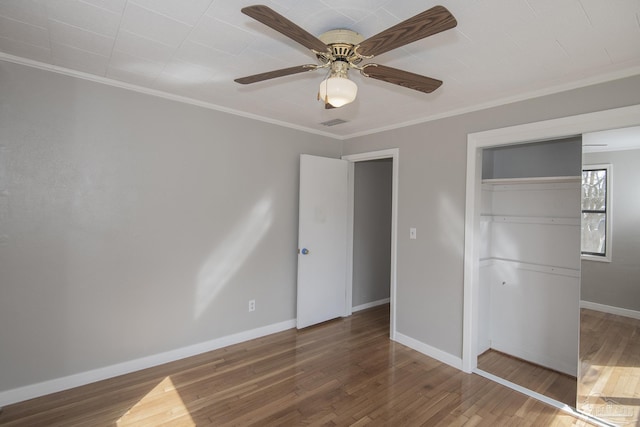 unfurnished bedroom featuring a ceiling fan, wood finished floors, baseboards, ornamental molding, and a closet